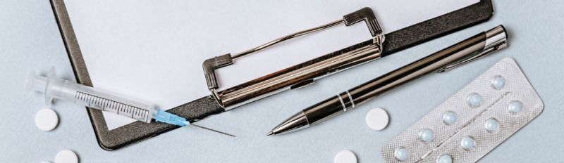 bolígrafo, tabla de apuntes, medicamentos, jeringa